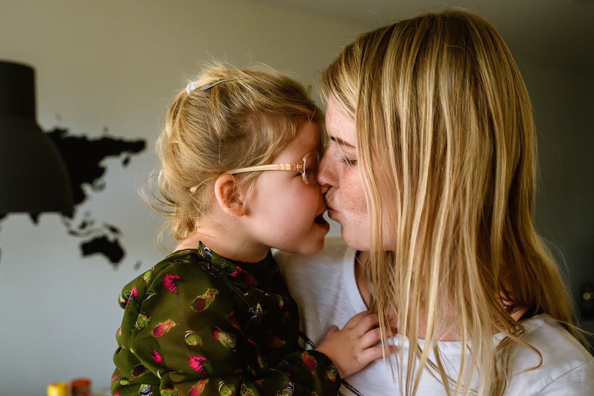 Meisje met bril krijgt kus van moeder