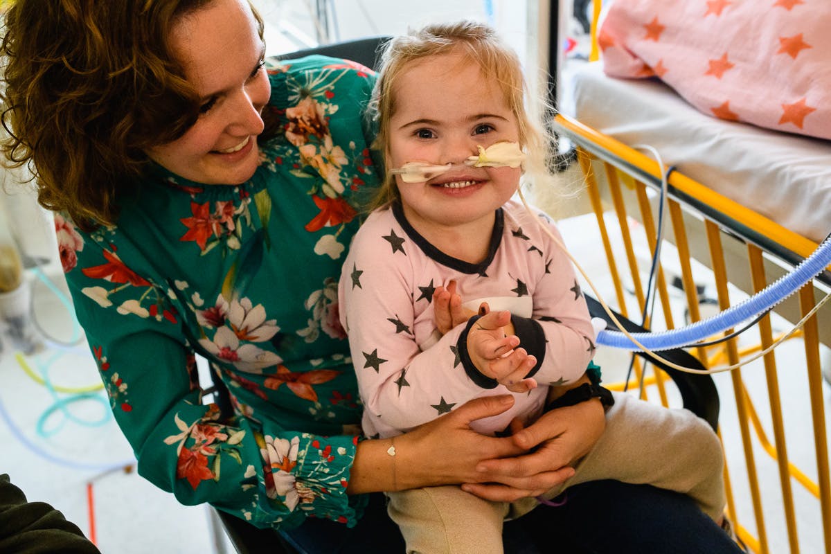 Kind lachend bij moeder op schoot in het ziekenhuis