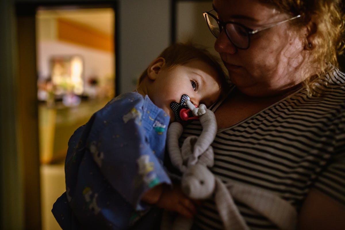 Kind met speen ligt tegen moeder aan