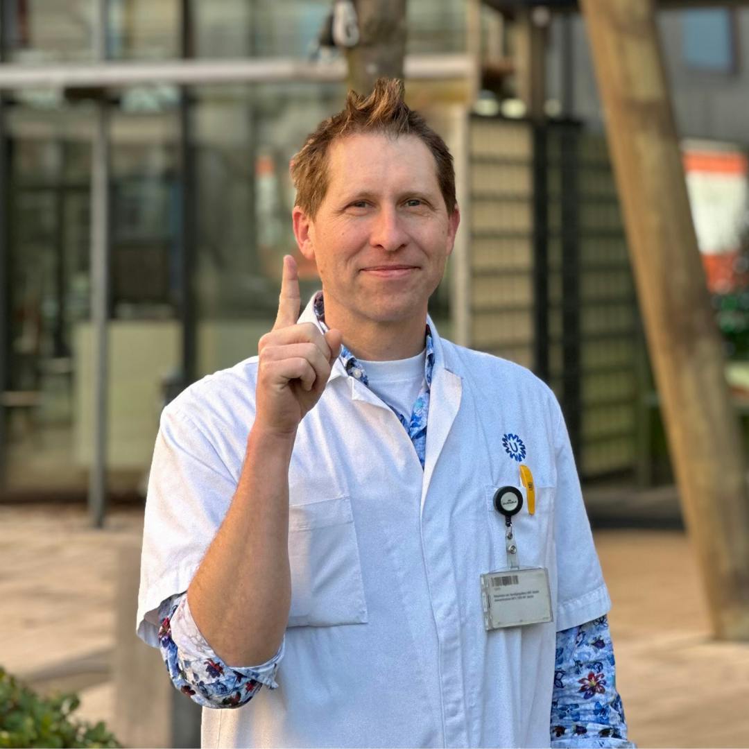 Mannelijk arts in witte jas met opgestoken vinger